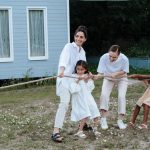 A happy family enjoys a game of tug of war in a grassy field by a house.